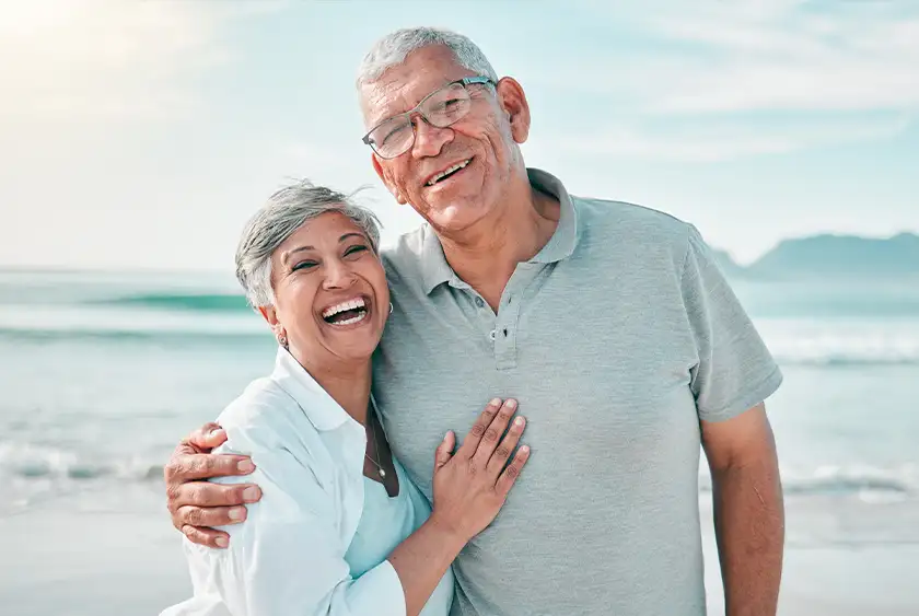 smiling older couple on the beach embracing medicare retirement and insurance services of florida brandon fl